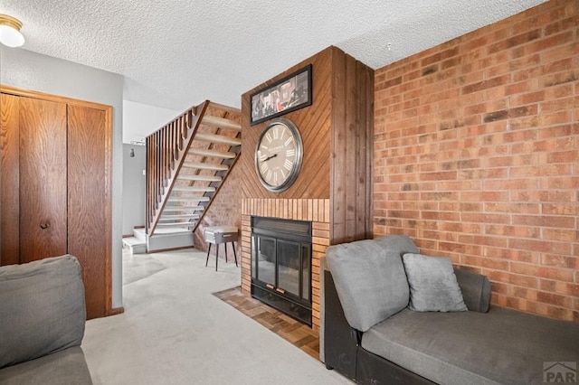 living room featuring a fireplace with flush hearth, light carpet, stairway, and a textured ceiling