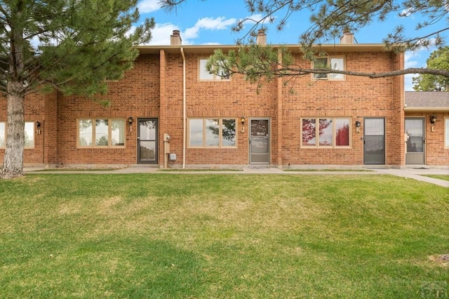 back of property with a chimney, a lawn, and brick siding