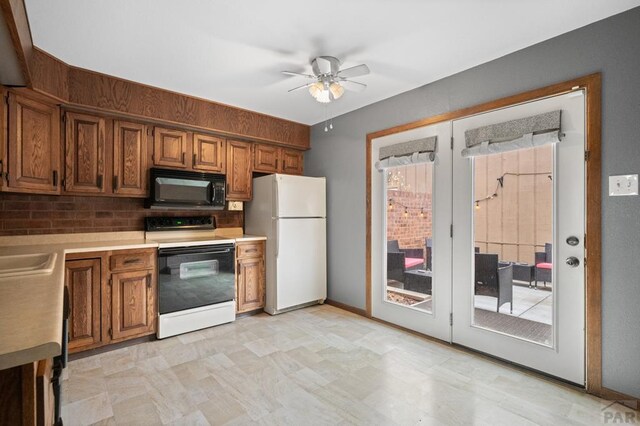 kitchen with light countertops, electric range oven, brown cabinetry, freestanding refrigerator, and black microwave