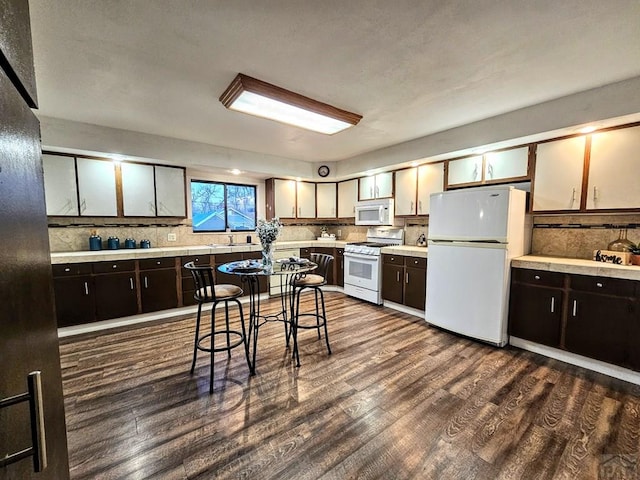 3112 Withers Ave, Pueblo, CO 81008 - kitchen featuring white appliances, tasteful backsplash, light countertops, dark wood-style flooring, and dark brown cabinets