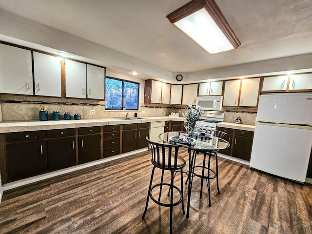 3112 Withers Ave, Pueblo, CO 81008 - kitchen featuring white appliances, a sink, tasteful backsplash, light countertops, and dark wood-style floors
