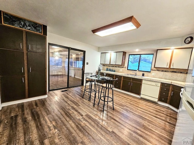 3112 Withers Ave, Pueblo, CO 81008 - kitchen with dishwasher, wood finished floors, decorative backsplash, light countertops, and a sink