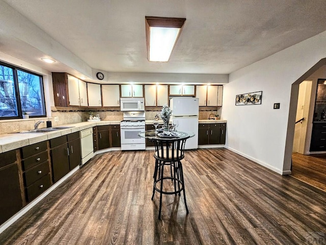 3112 Withers Ave, Pueblo, CO 81008 - kitchen with white appliances, a sink, dark wood-type flooring, backsplash, and baseboards