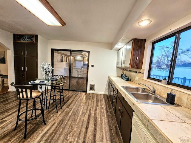 3112 Withers Ave, Pueblo, CO 81008 - kitchen with a sink, dark wood-style floors, baseboards, tile counters, and backsplash