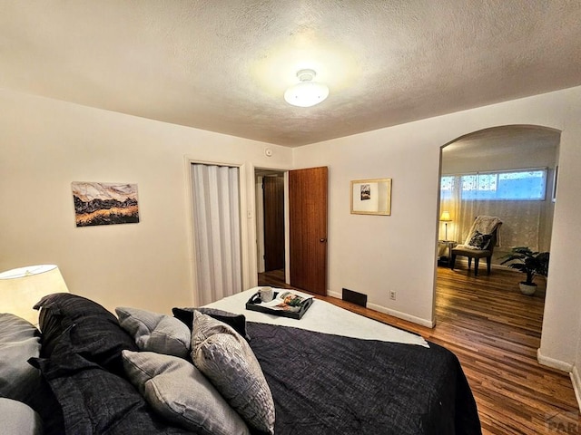 3112 Withers Ave, Pueblo, CO 81008 - bedroom with arched walkways, wood finished floors, baseboards, and a textured ceiling