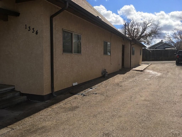 view of side of home featuring fence and stucco siding