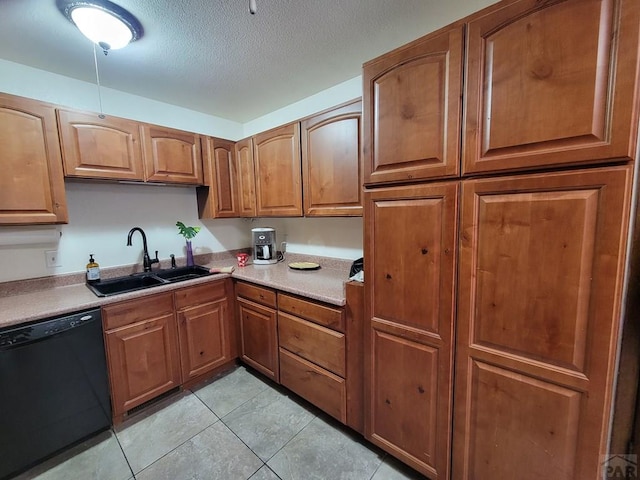 kitchen featuring brown cabinetry, a textured ceiling, black dishwasher, light tile patterned flooring, and a sink