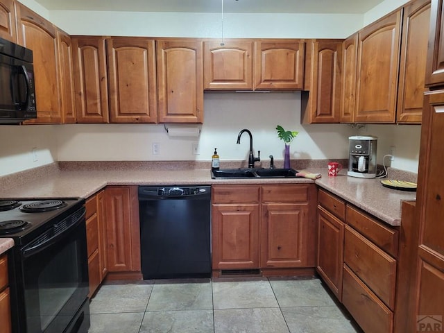 kitchen featuring a sink, light countertops, brown cabinetry, black appliances, and light tile patterned flooring