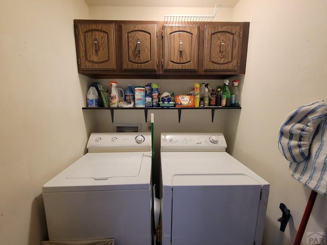 clothes washing area with washer and dryer and cabinet space