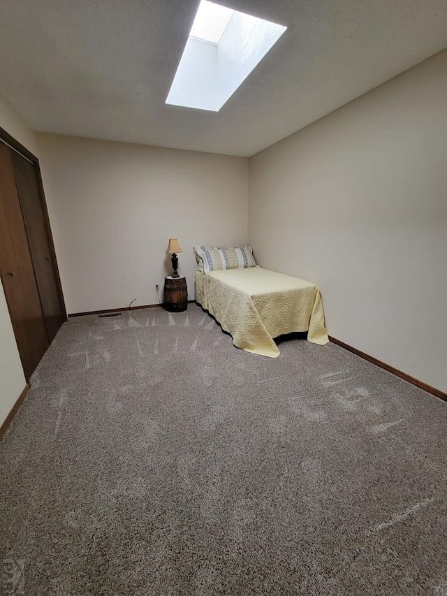 unfurnished bedroom featuring a skylight, carpet flooring, and baseboards