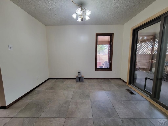 spare room with visible vents, baseboards, and a textured ceiling