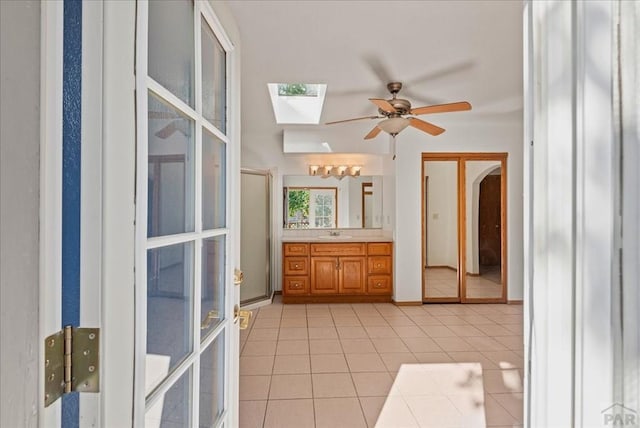 bathroom with a skylight, a ceiling fan, vanity, tile patterned floors, and an enclosed shower