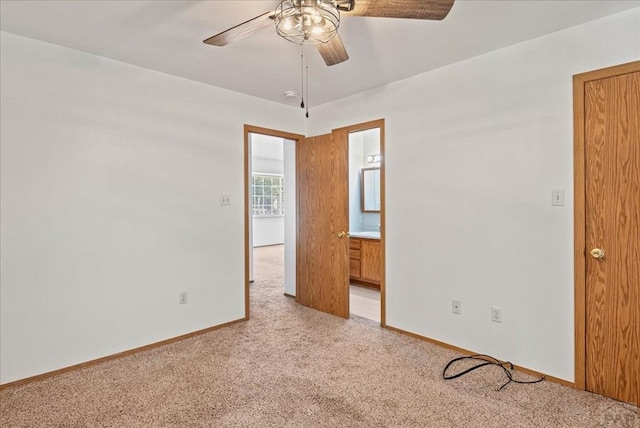 unfurnished bedroom featuring light carpet, a ceiling fan, baseboards, and connected bathroom