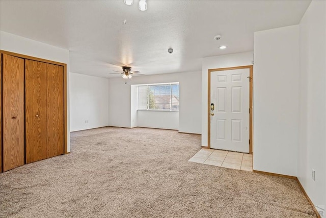 interior space featuring light carpet, baseboards, and a ceiling fan