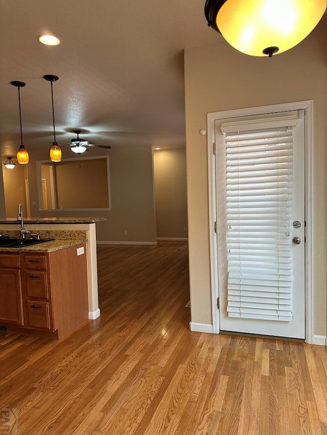 573 S Putter Dr, Pueblo West, CO 81007 - kitchen featuring a ceiling fan, brown cabinets, light wood-style floors, decorative light fixtures, and open floor plan