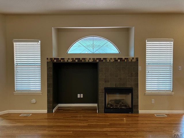 573 S Putter Dr, Pueblo West, CO 81007 - unfurnished living room with wood finished floors, a fireplace, and plenty of natural light
