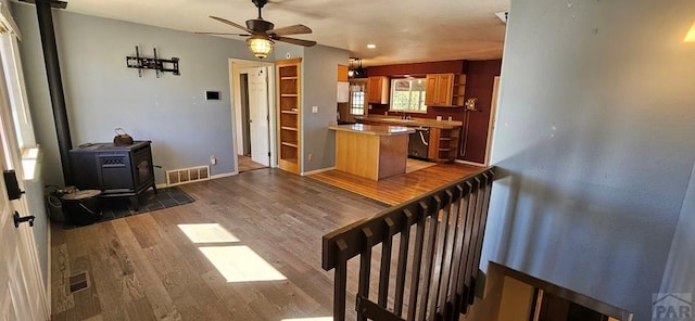 kitchen featuring a wood stove, a peninsula, visible vents, and wood finished floors