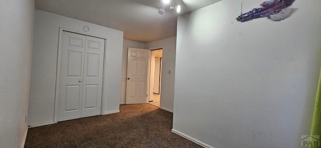 hall with dark colored carpet and baseboards