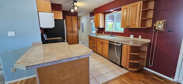 kitchen with pendant lighting, open shelves, stainless steel appliances, a sink, and a peninsula