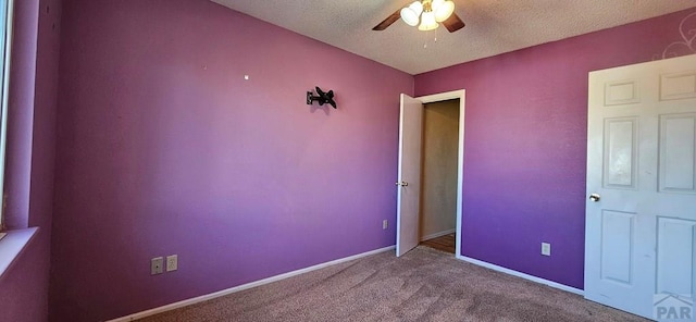 unfurnished room with a textured ceiling, carpet floors, a ceiling fan, and baseboards