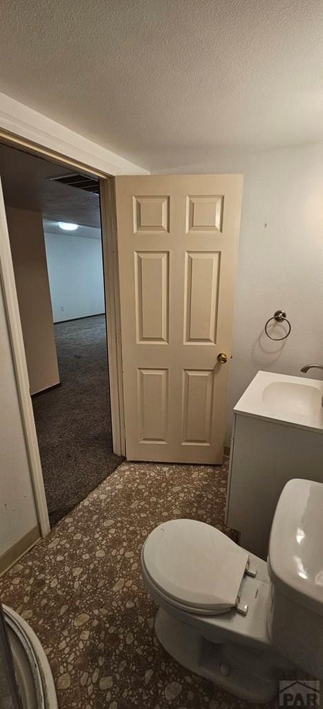 bathroom with toilet, a textured ceiling, and a sink