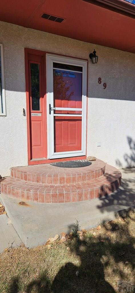 property entrance featuring visible vents and stucco siding