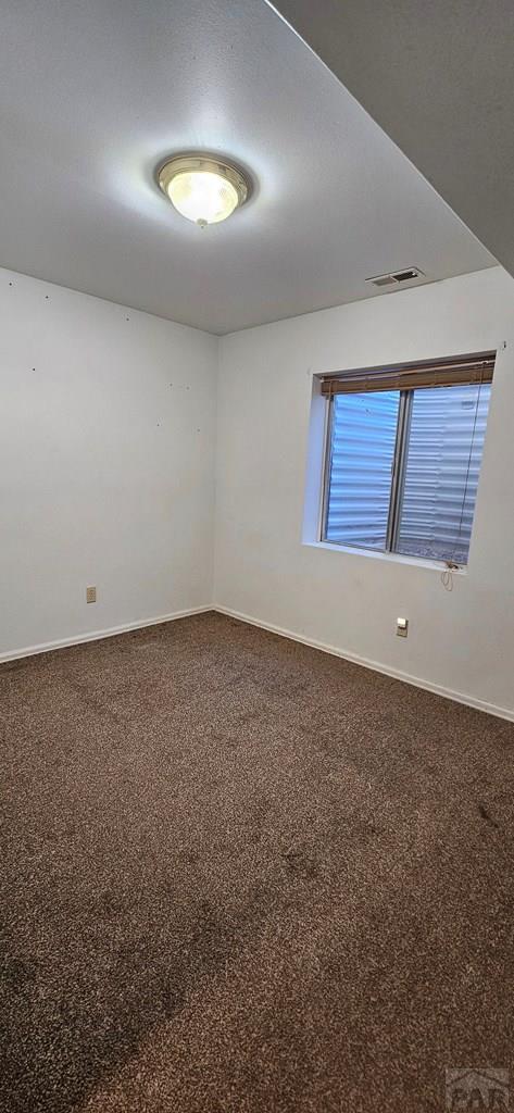 carpeted spare room with visible vents and baseboards