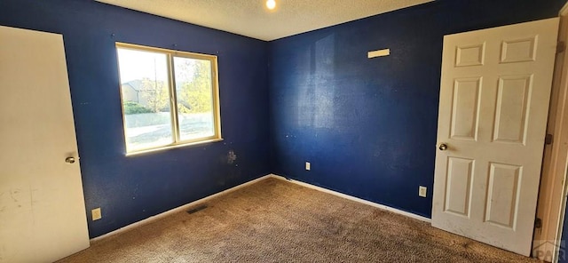 carpeted spare room featuring visible vents, baseboards, and a textured ceiling