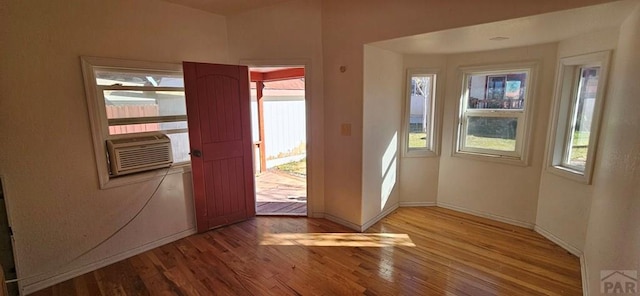 entryway with a wealth of natural light, baseboards, cooling unit, and light wood finished floors