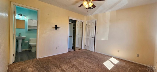 bedroom featuring lofted ceiling, carpet flooring, visible vents, baseboards, and ensuite bath