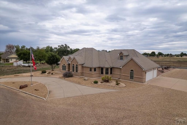 view of front of property with a tiled roof, concrete driveway, and stucco siding