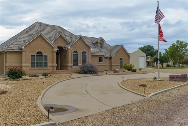 view of front facade featuring concrete driveway, a tiled roof, and stucco siding