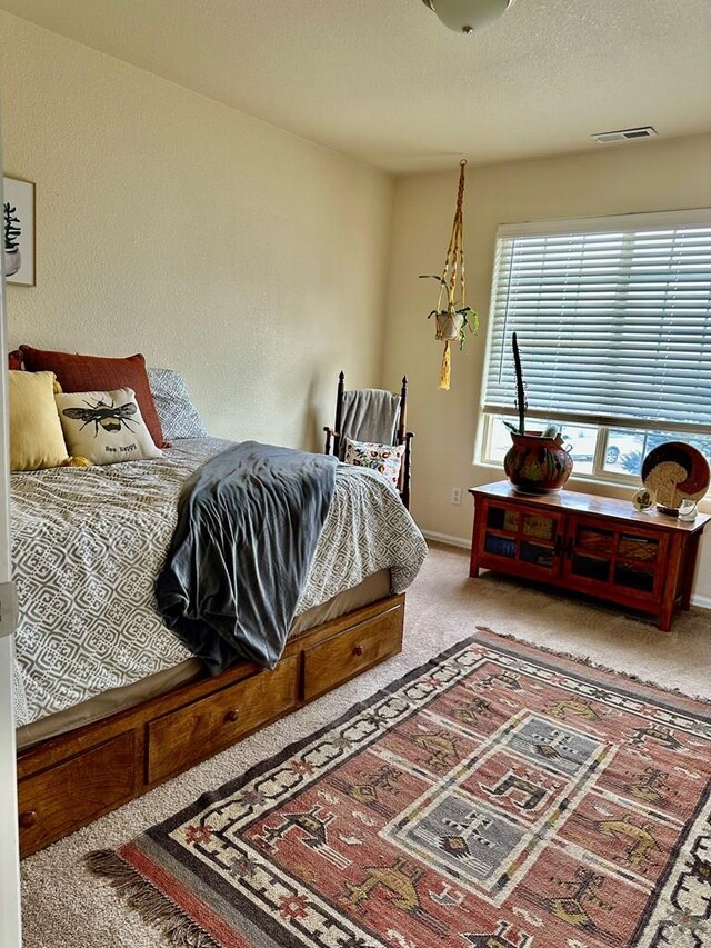 bedroom with baseboards, visible vents, a textured ceiling, and light colored carpet