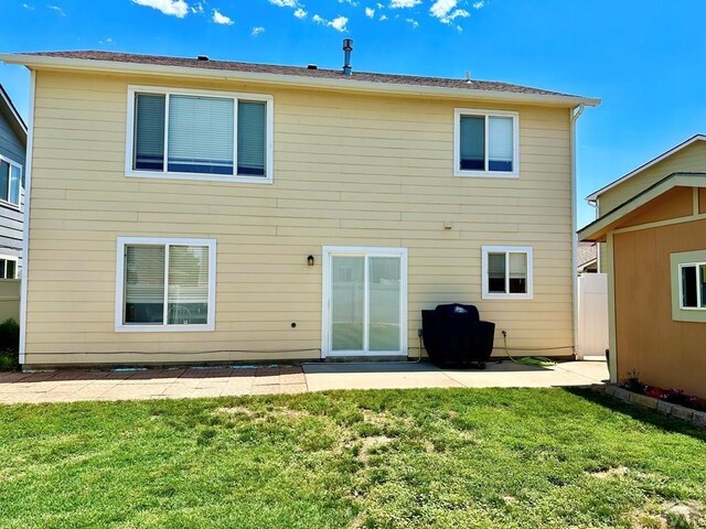 rear view of house with a lawn and a patio