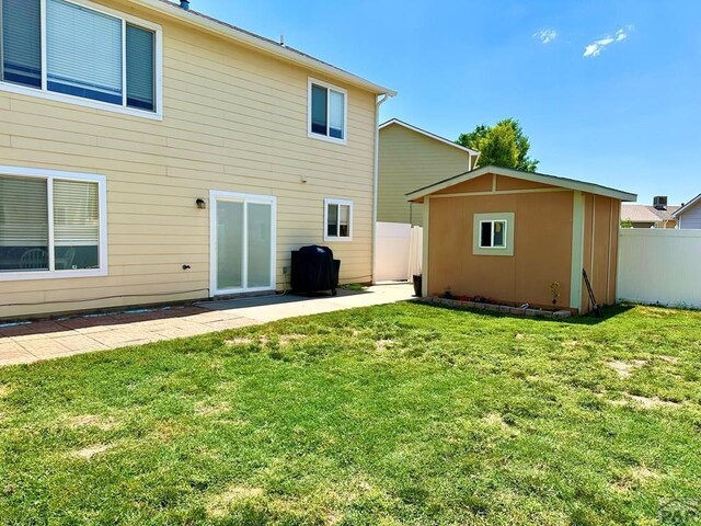 back of property featuring a yard, an outdoor structure, a storage shed, and fence