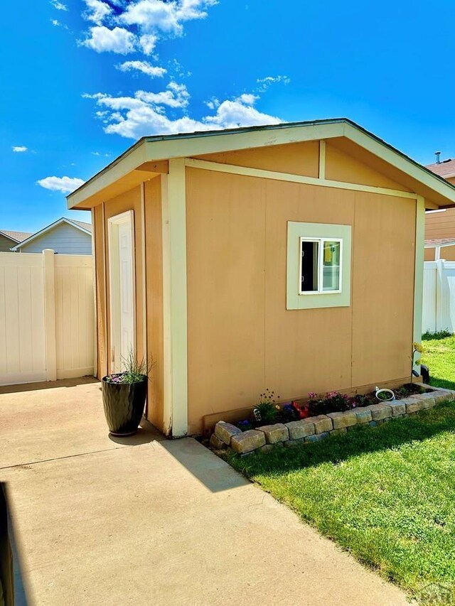 view of home's exterior featuring a patio area, a lawn, an outdoor structure, and fence