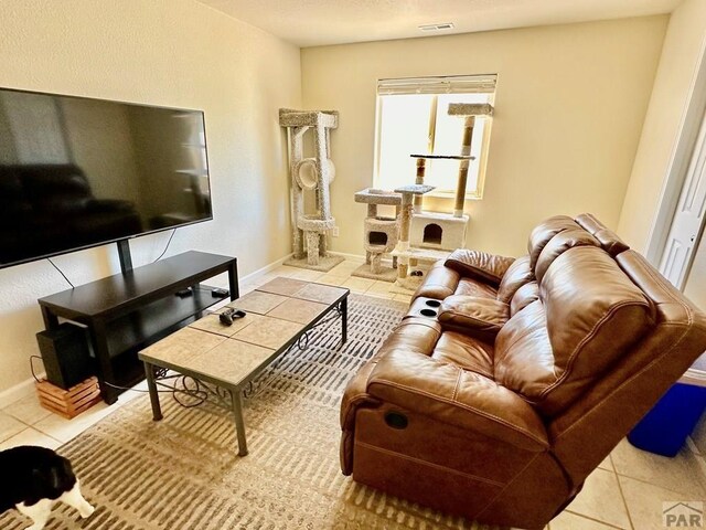 living room with light tile patterned flooring, visible vents, and baseboards