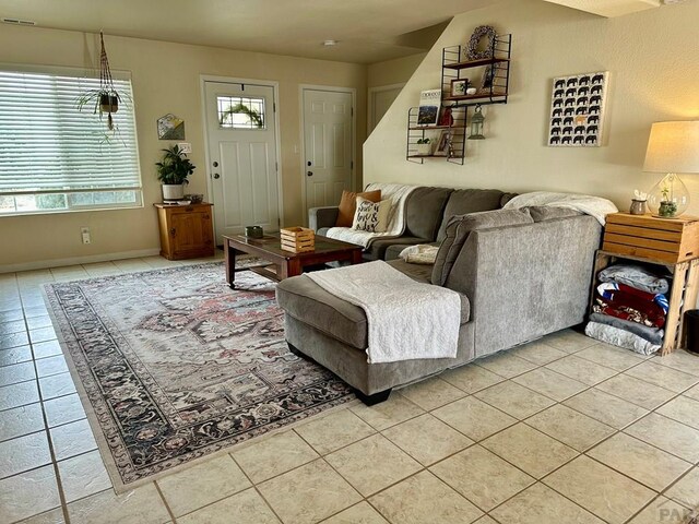 living room with light tile patterned floors, visible vents, and a wealth of natural light