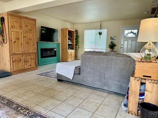 living area featuring light tile patterned floors and a glass covered fireplace