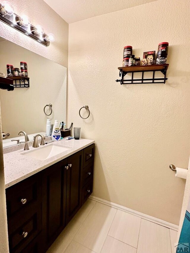 bathroom with tile patterned flooring, baseboards, and vanity