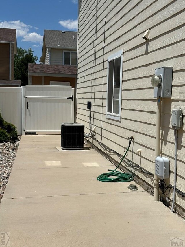 view of property exterior with central AC, a patio area, fence, and a gate