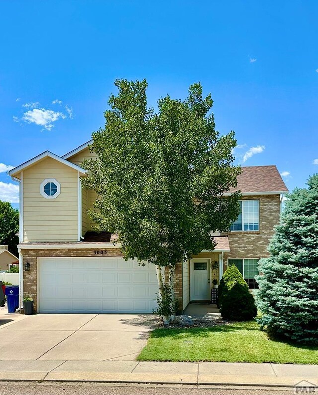 view of property hidden behind natural elements featuring concrete driveway, brick siding, and an attached garage