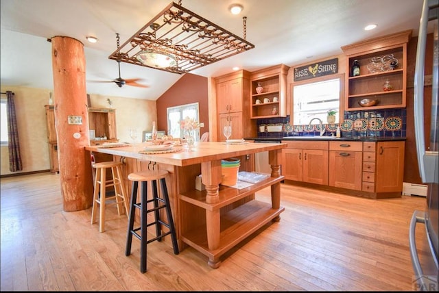 kitchen featuring a healthy amount of sunlight, light wood-style floors, open shelves, and lofted ceiling