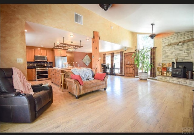 living room with a towering ceiling, light wood-style floors, and visible vents