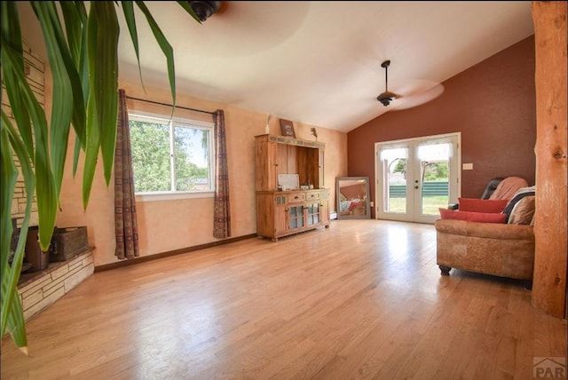 sitting room with lofted ceiling, french doors, a healthy amount of sunlight, and wood finished floors