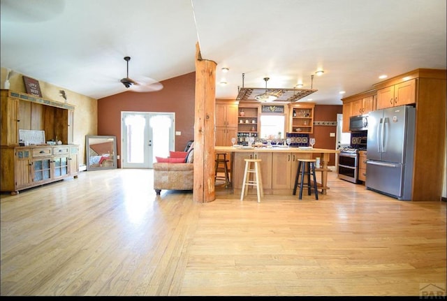 kitchen featuring appliances with stainless steel finishes, a breakfast bar, open floor plan, and light wood-style floors