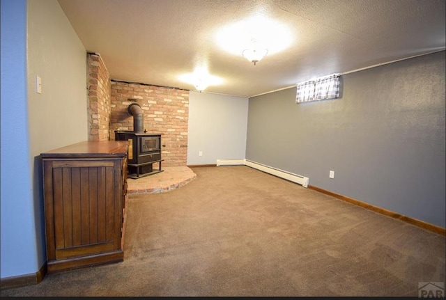 finished basement with a baseboard heating unit, carpet, a wood stove, and a textured ceiling