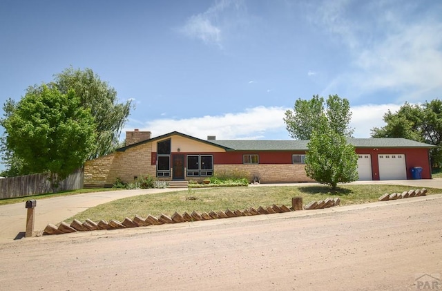 view of front of property with driveway, an attached garage, a chimney, and fence