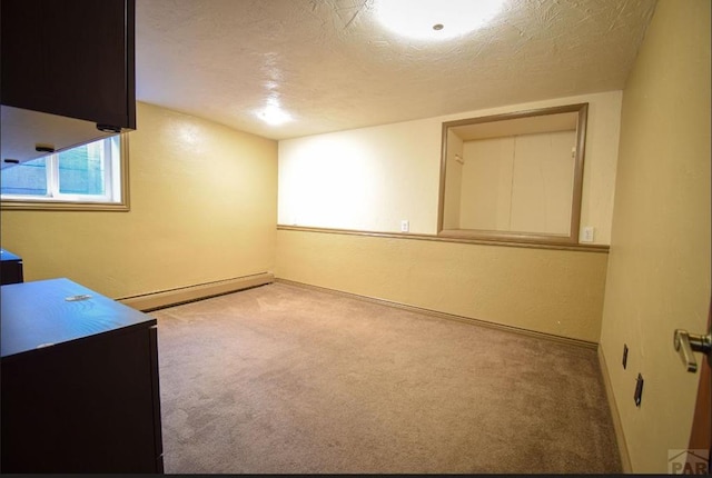 empty room with a textured ceiling, carpet floors, and baseboard heating