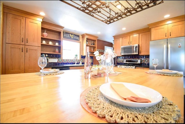 kitchen featuring open shelves, stainless steel microwave, wooden counters, stove, and a sink